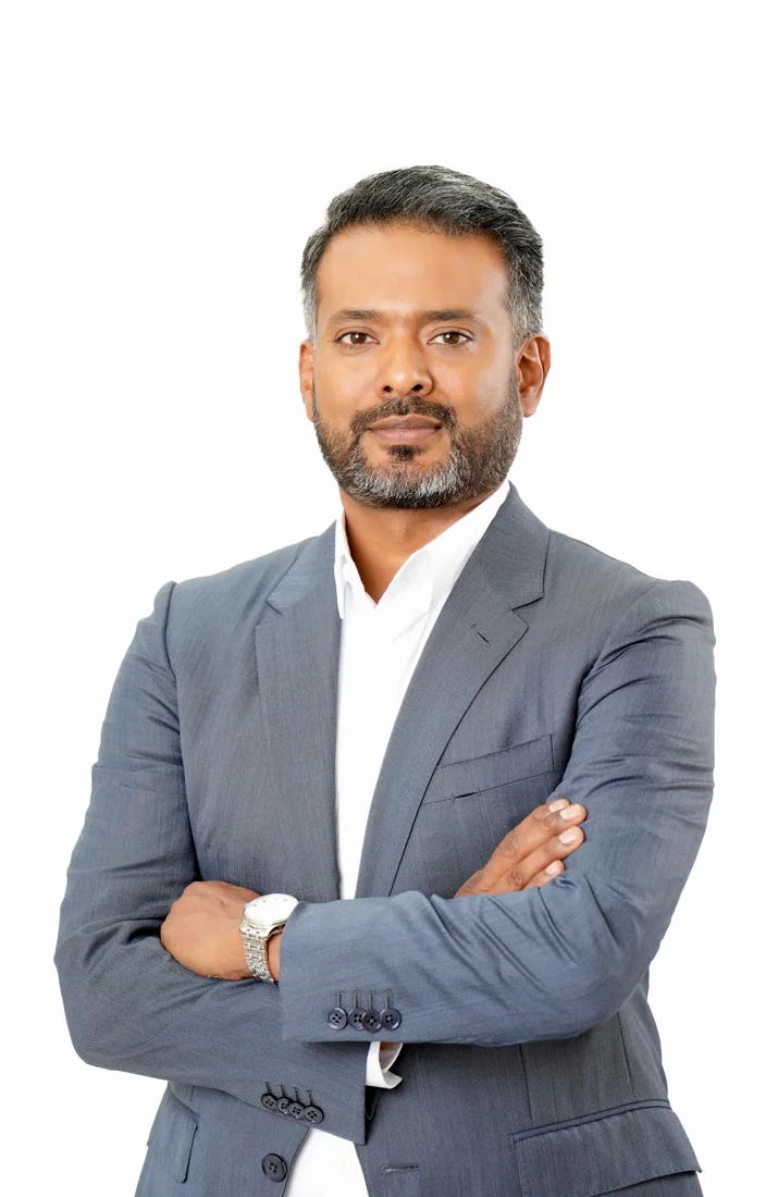 Ash Khan with arms crossed, wearing a grey suit